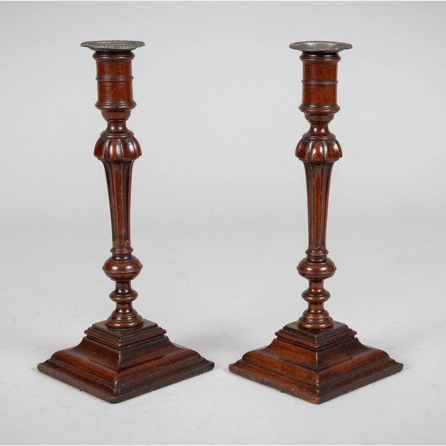 A handsome pair of antique English mahogany candlesticks, each raised on a stepped square base with well-defined molding,...