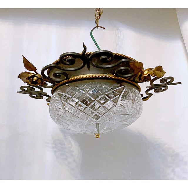 A vintage hand cut patterned glass flush mount fixture with a very heavy ornate Iron rim painted in black and gold That...