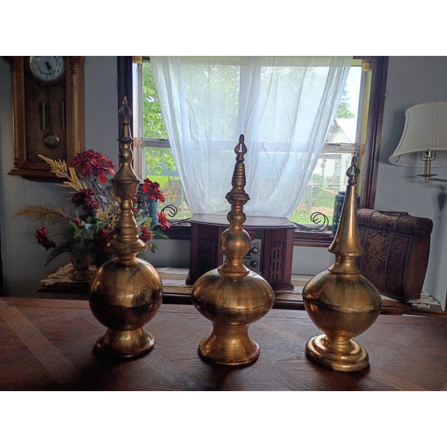 Set of three, thin, lightweight and hollow weight iron bronze/gold colored set of 3 Simone Finials. Part of the Home...