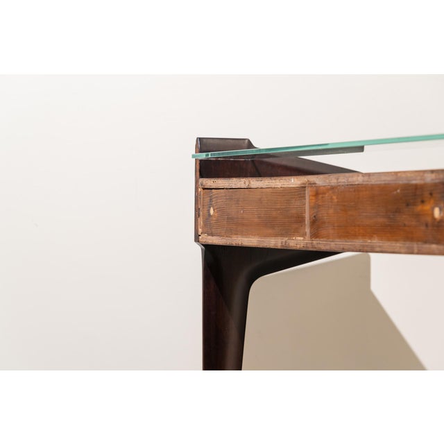 Mid-Century Italian console table from the 1950s, made of wood. It features slender and elegant proportions. The main body...