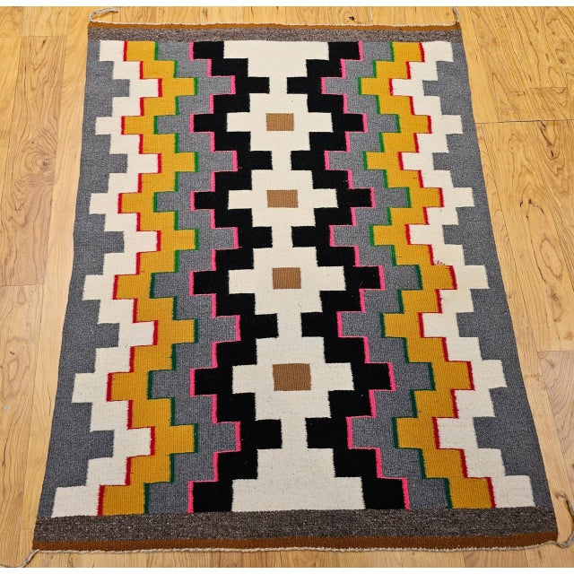 A vibrant and authentic Vintage Native American Navajo rug, this striking textile features a bold geometric tribal pattern...