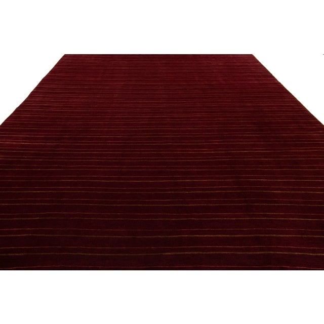 This contemporary Tibetan weave rug showcases a striking striped design in various shades of brown that immediately...