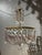 Elegant 1950s chandelier featuring a beautifully detailed brass frame and adorned with Bohemian crystal prisms and...