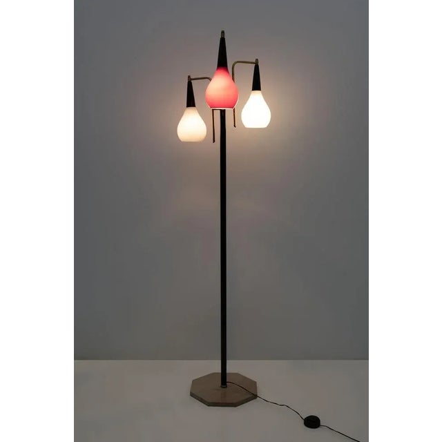 Floor lamp in brass, black lacquered metal, colored blown glass and trevertine base. Produced by Stilnovo in Italy in the...