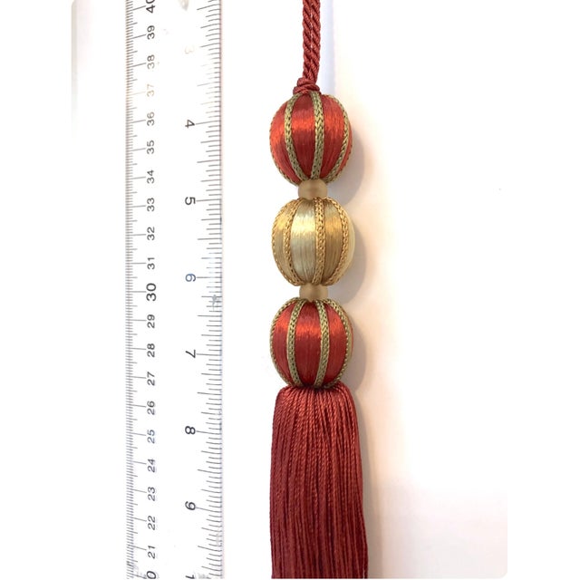 Festive satin beaded key tassels in a terracotta - red with gold details. Wrapped satin beads are surrounded by gold and...