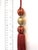 Festive satin beaded key tassels in a terracotta - red with gold details. Wrapped satin beads are surrounded by gold and...