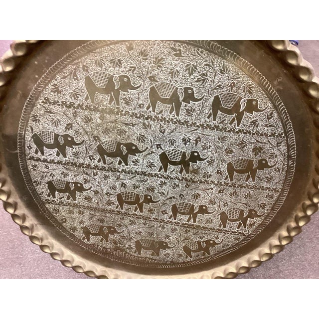 Impressive extra-large vintage brass tray featuring an intricately engraved procession of elephants surrounded by dense...
