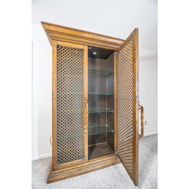 This distinctive cabinet features a warm gold leaf–style finish over a carved wood frame, paired with intricately...