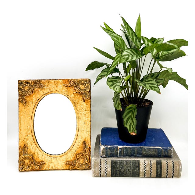 Captivating and richly textured gilt wood mirror frame with an oval opening and floral corner detailing. The finish has...