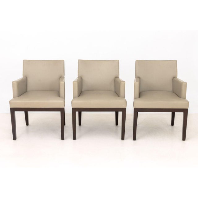 Set of Six Christian Liaigre Style Dining Armchairs, with taupe upholstery on wood legs. 33" H x 24.5" W x 25" D; seat:...
