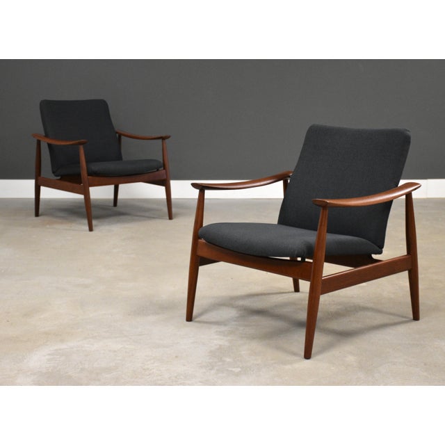 A pair of sleek mid century modern teak model 138 easy lounge chairs with charcoal grey fabric newly reupholstered...
