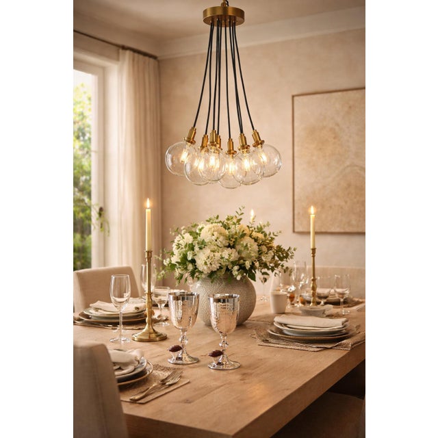 Striking RH-inspired modern cluster chandelier featuring seven oversized clear glass globes suspended from a satin brass...