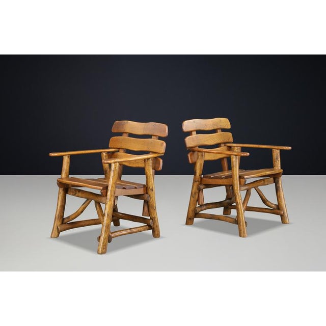 A remarkable pair of sculptural solid oak armchairs, handcrafted in France during the 1950s. These highly expressive...