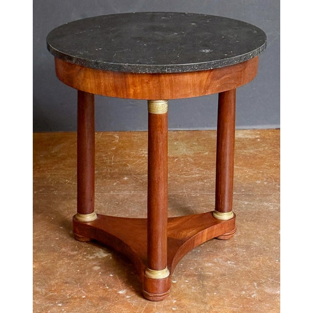 A handsome French round table or gueridon in the Empire style, featuring a circular top of figured black marble (25.5"...