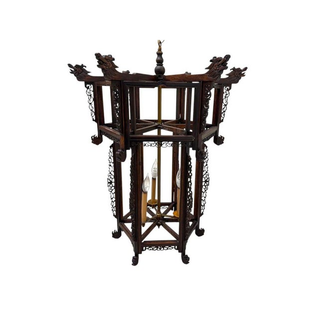A hexagonal Chinese hardwood three light lantern, showcasing intricate open fretwork panels on all six sides. Each panel...