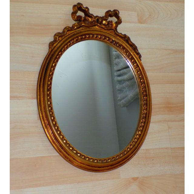 Vintage Italian Florentine Gilded Oval Mirror Ribbon Bow Accent Ornate oval wall mirror featuring a carved ribbon bow top,...