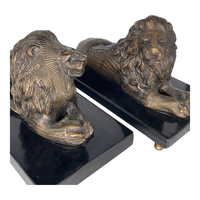A stately pair of Bombay Company solid brass lion bookends resting on polished black marble bases. Each lion features...