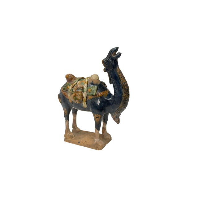 This captivating ceramic sculpture depicts a Bactrian camel rendered in rich sancai-style glazes, capturing the spirit of...