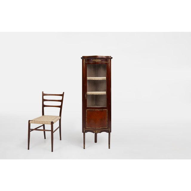 A refined French corner display cabinet from the mid-20th century, crafted in the Louis XV style. The piece features a...