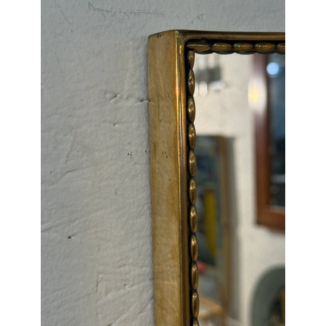 A large Italian mid century rectangular wall mirror set in a slender gilt frame with delicate beaded detailing along the...