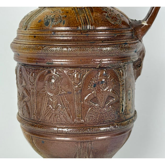 A rare early 17th Century German impressed raeren stoneware jug. The body of the jug features a frieze of women in...