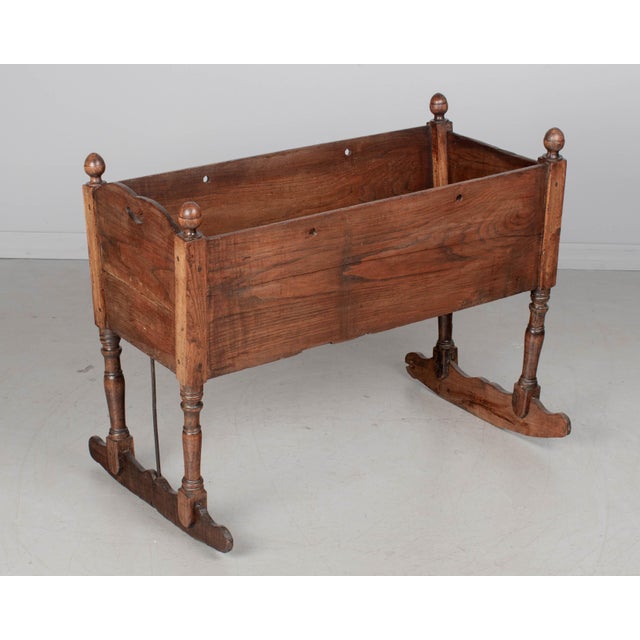 A 19th century French Country baby crib, hand crafted will planks of chestnut, with turned oak spindle legs and finials....