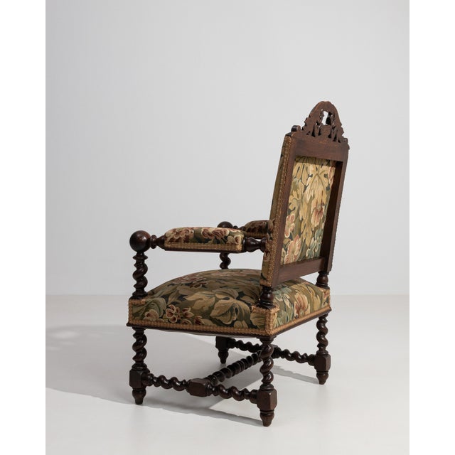 A stately Jacobean-style armchair crafted from oak, featuring bold carved details and a strong architectural frame. The...