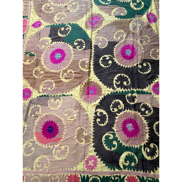 Hand-embroidered Suzani panel from Uzbekistan — large round medallions in tan, green and black with magenta centres on a...