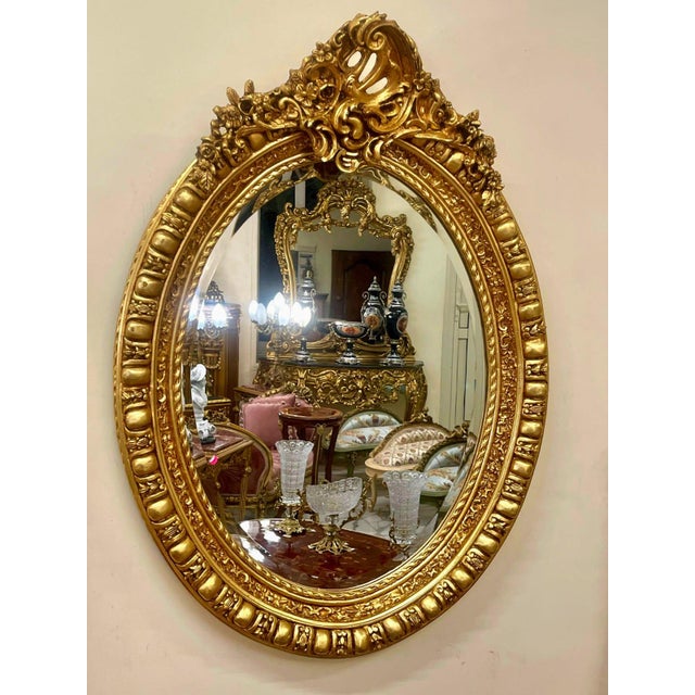 Elegant Italian style vertical oval wall mirror featuring an ornate gold leaf frame beautifully enhanced with decorative...