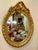 Elegant Italian style vertical oval wall mirror featuring an ornate gold leaf frame beautifully enhanced with decorative...