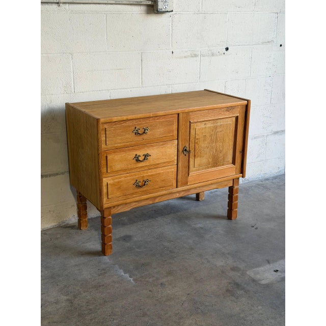 This compact storage piece features a classic rectilinear form with decorative paneling and carved stacked legs. It...