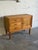 This compact storage piece features a classic rectilinear form with decorative paneling and carved stacked legs. It...