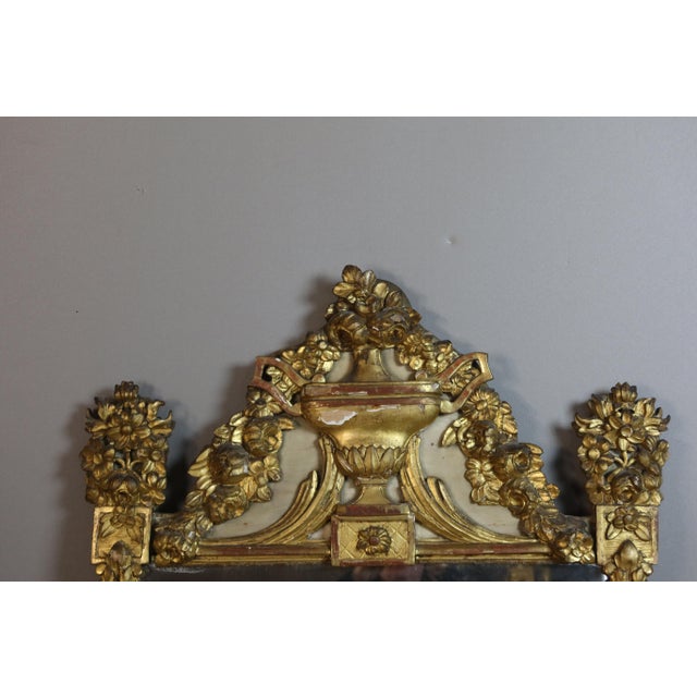 Large, carved, giltwood mirror from the late 18th century. It features an urn at the top, richly decorated with flowers...