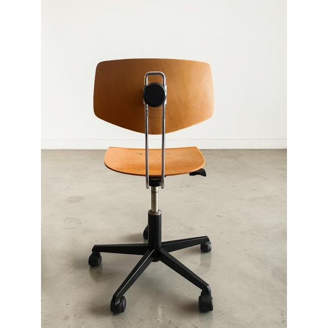 Minimalist vintage swivel chair with a beautifully aged molded plywood seat shell and a striking black star base on...