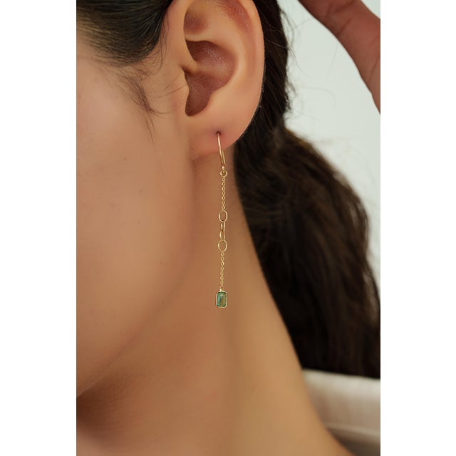 These drop link chain earrings featuring 0.59 carats of natural emeralds set in 14K yellow gold. The emerald secured in...
