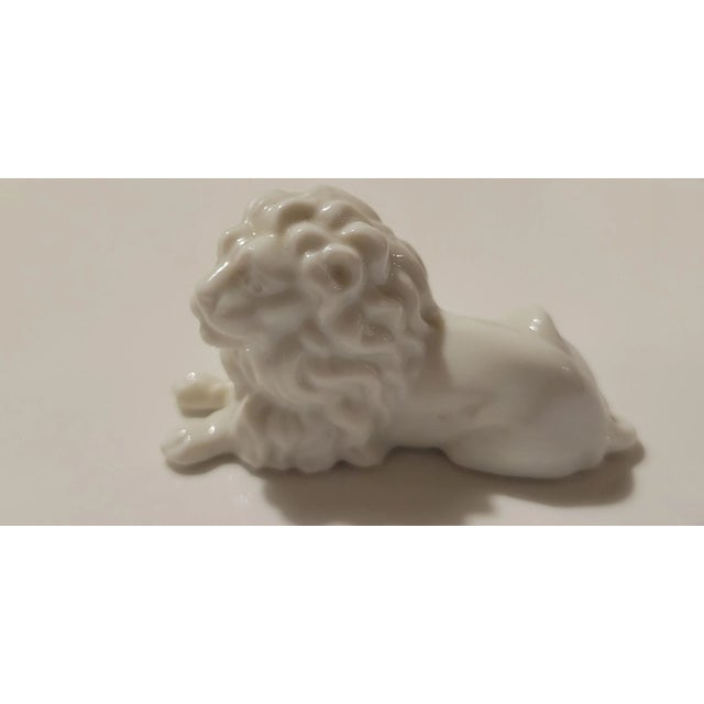 A diminutive yet dignified presence, this vintage porcelain lion figurine captures the majesty of its subject in a moment...
