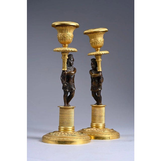 Pair of Directoire period candlesticks with Nubian figures, early 19th century. Gilt and patinated bronze candlesticks,...