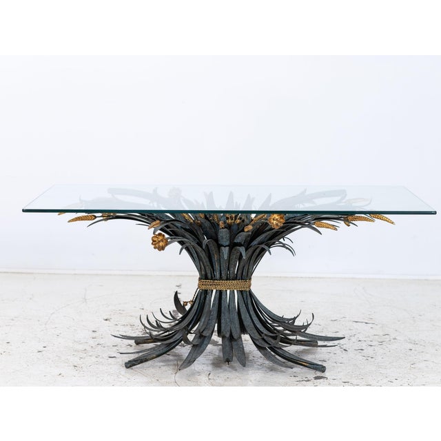 This period French Hollywood Regency coffee table features a verdigris and gilt metal sheaf of wheat base beneath a...