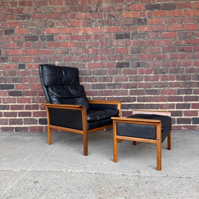 Mid-century modern lounge chair and ottoman designed by Knud Sæter. The chair features a rosewood frame with black leather...