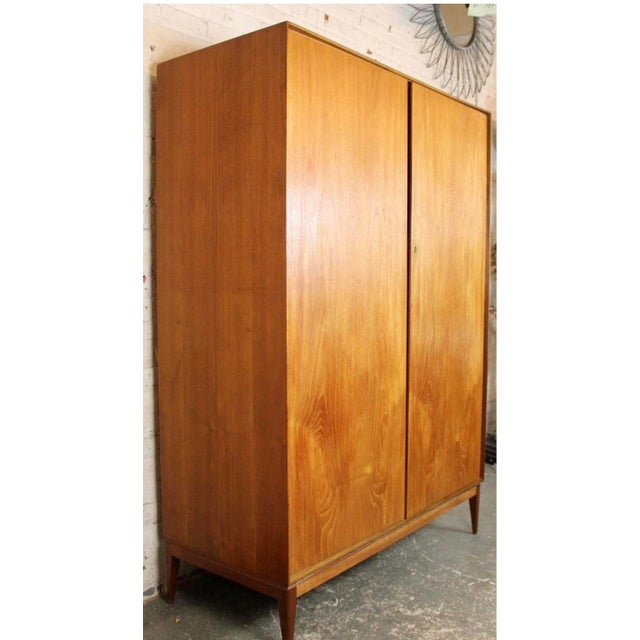 A sleek mid-century armoire by A.H. McIntosh (1960s, Scotland), crafted in warm teak veneer. With minimalist lines, subtle...