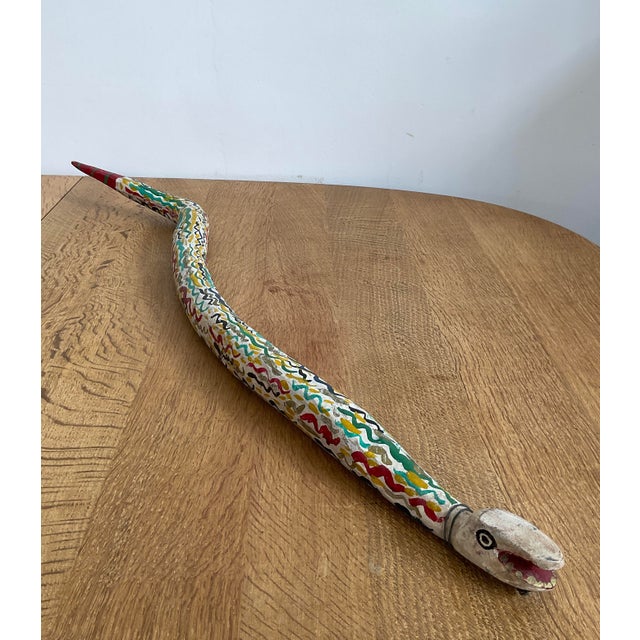 Add a bold statement piece to your decor with this whimsical, hand-carved wooden folk art snake. Featuring an intricate,...