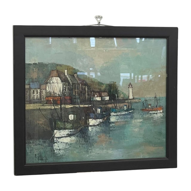Vintage framed harbor painting depicting a coastal village with moored fishing boats, a lighthouse, and waterfront...