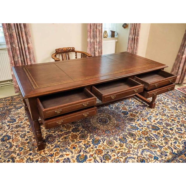 Large writing desk made of solid oak with a writing board covered with leather. The leather writing surface is decorated...