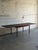 This minimalist wooden dining table features a clean rectangular top that smoothly expands with two pull-out leaves to...