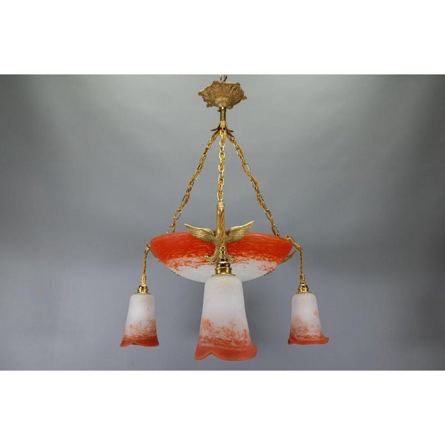 French Empire-style chandelier with a signed glass bowl and bronze swans, circa 1925. Striking chandelier featuring a red...