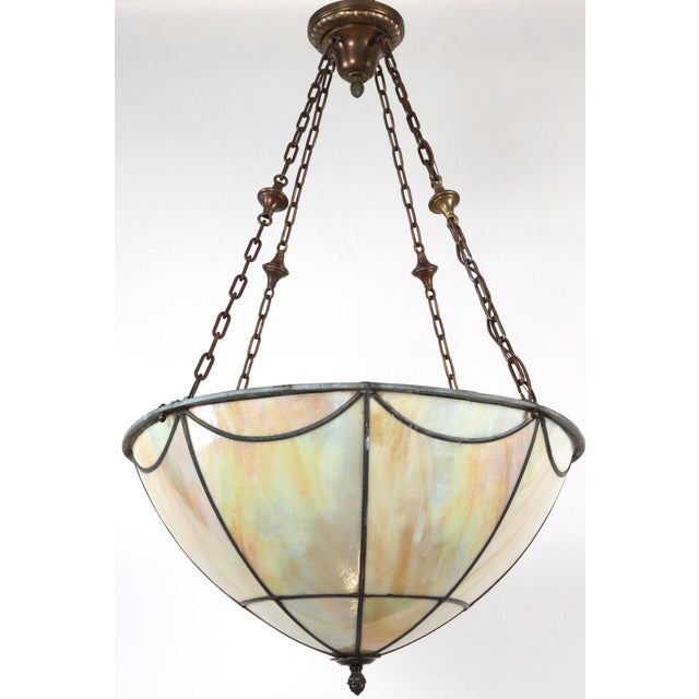 Arts & Crafts style bowl pendant light featuring iridescent slag glass panels joined together by lead to create a...