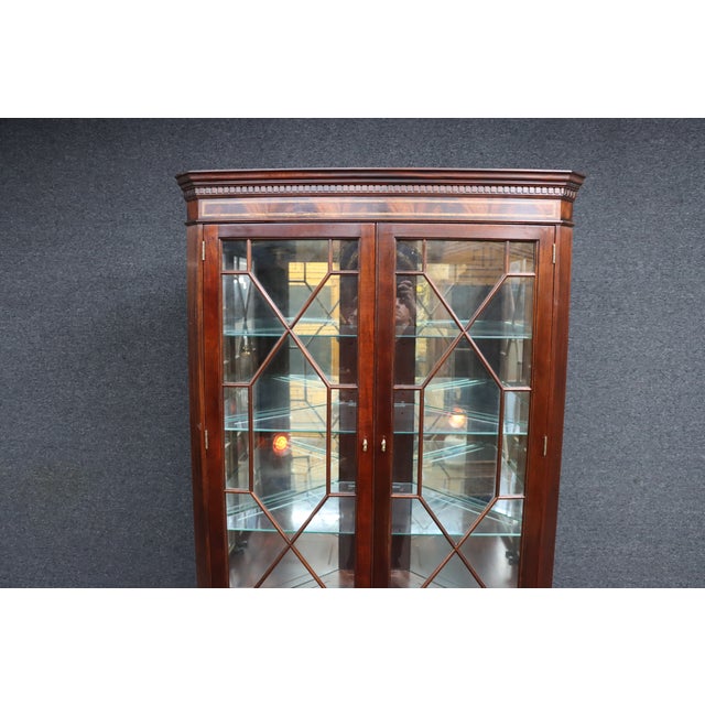 Mahogany corner cabinet by Stickley with glass-paneled doors and interior glass shelves. Features a classic design with...