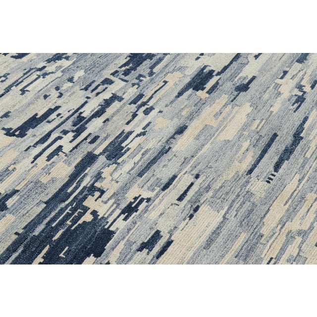 Hand-knotted in wool, this 5x6 modern abstract rug features blue and cream white tones underscore geometric patterns like...
