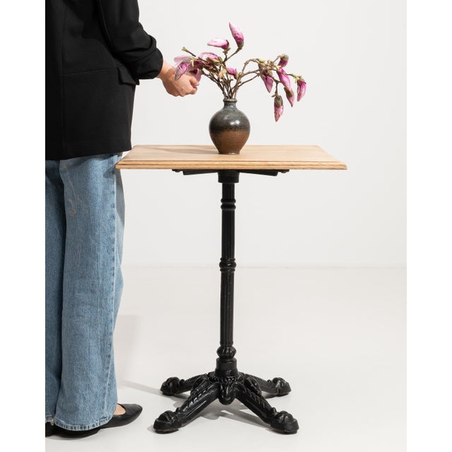 An authentic French bistro table combining a sturdy cast iron base with a warm oak top. The contrast of materials creates...