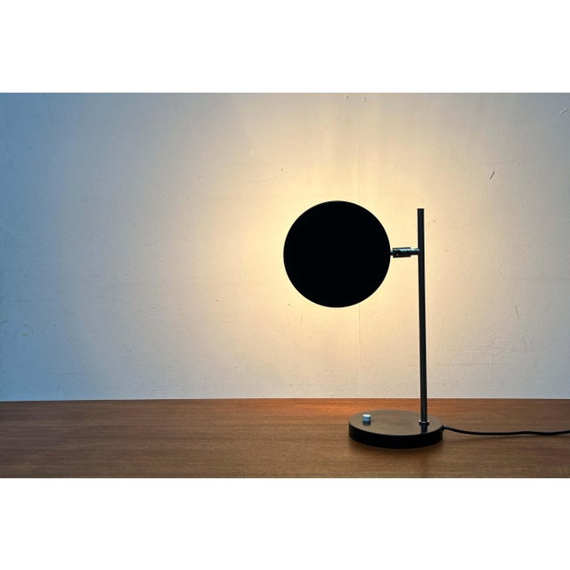 Rare Mid Century table lamp. Probably from Kaiser Leuchten. A minimalist design. The flat, round metal shade is finished...
